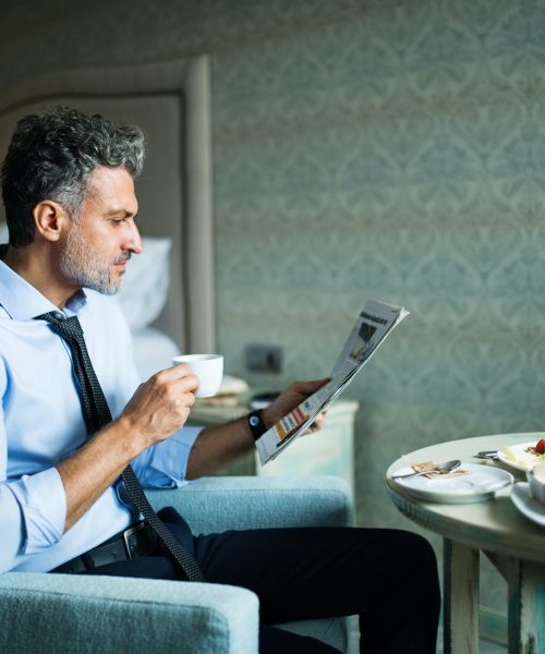 Mature businessman having breakfast in a hotel room.